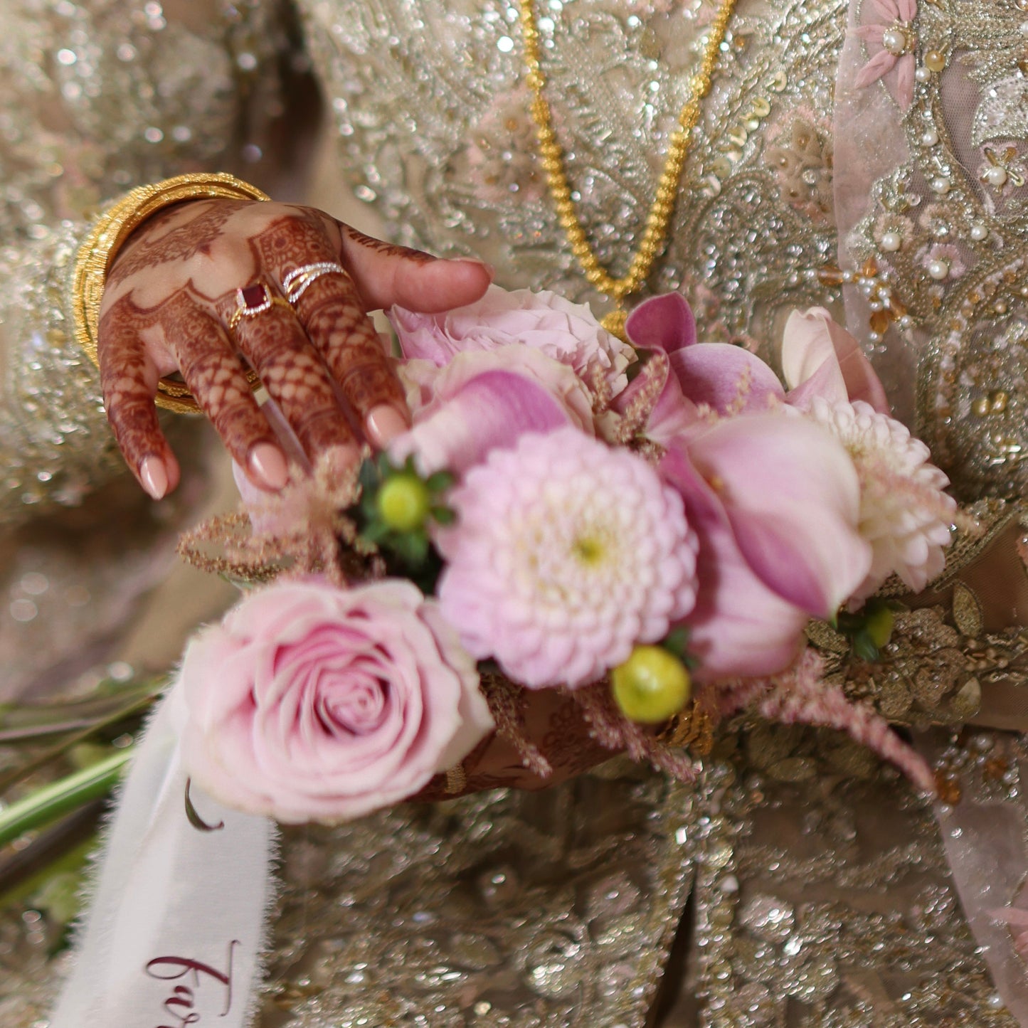 Close-up of a bouquet of pink peonies, Dhalias, roses, held by a person in a bridal outfit.