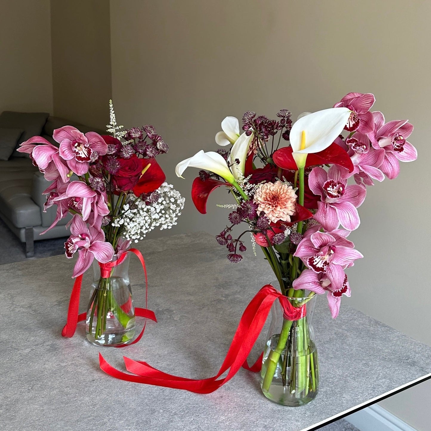 Two floral arrangements with pink and red flowers on a table.