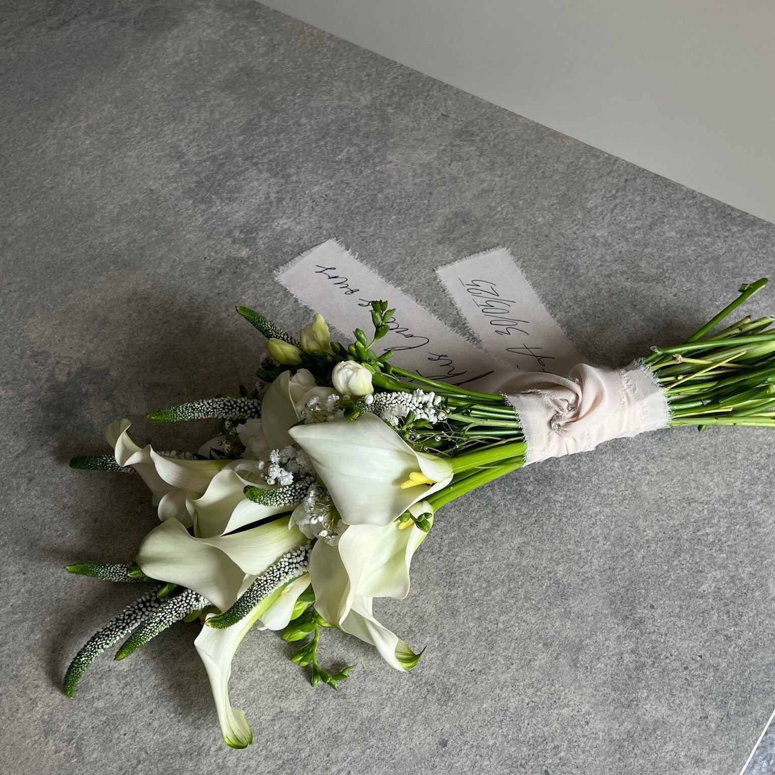 Bouquet of white flowers with greenery on a gray surface