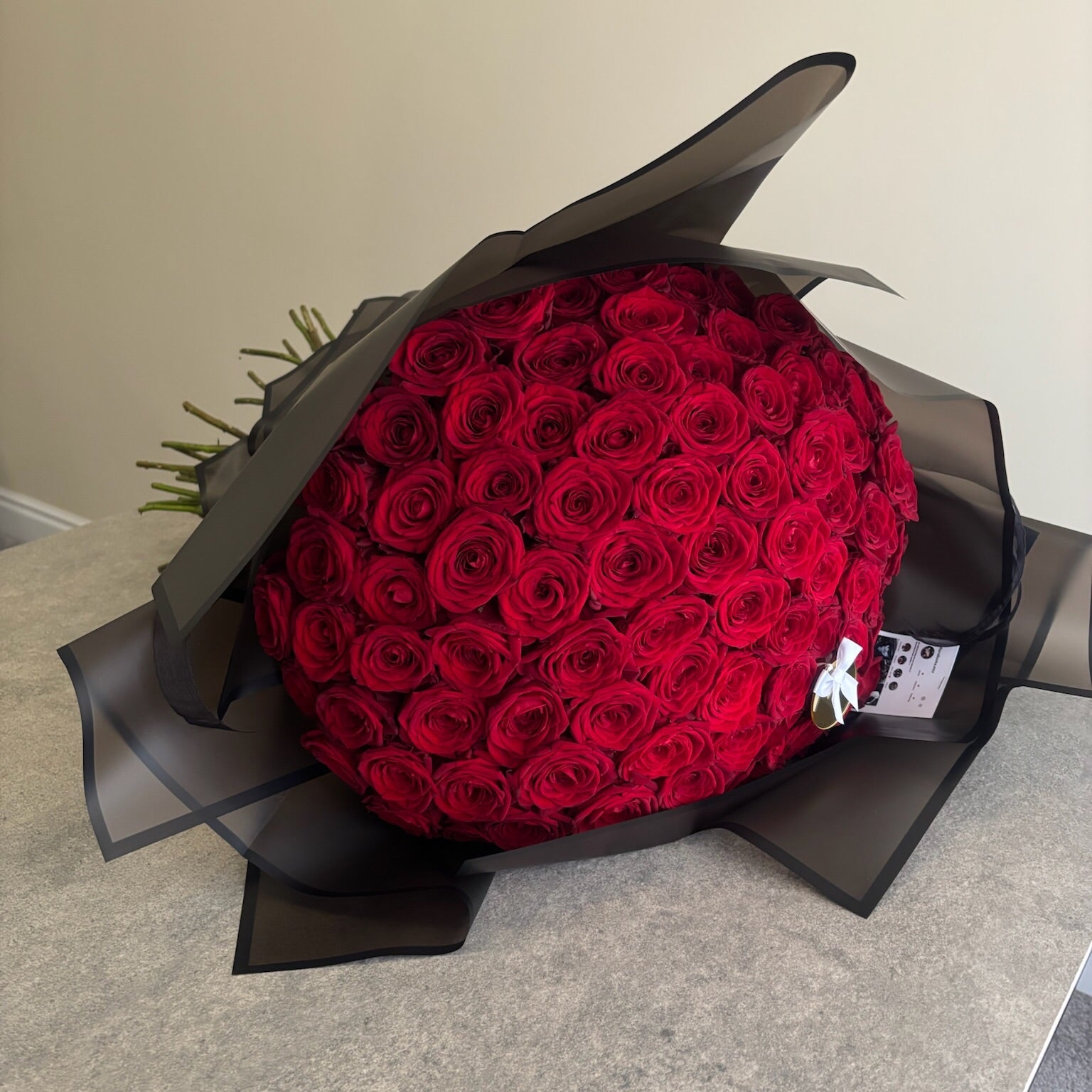 Bouquet of red roses wrapped in black paper on a neutral background