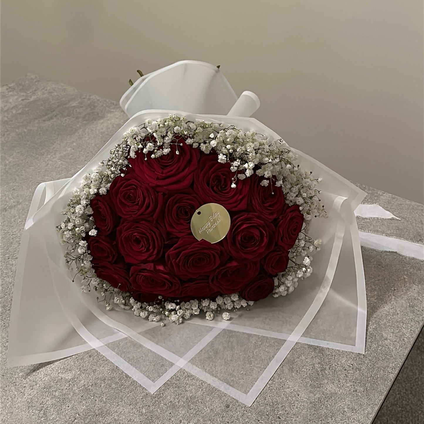 Bouquet of red roses in velour wrapping with baby's breath on a light surface