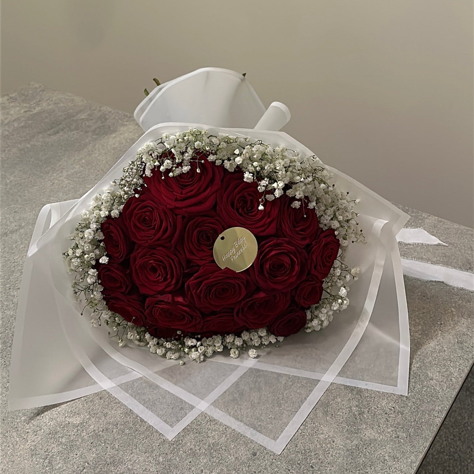Bouquet of red roses in velour wrapping with baby's breath on a light surface