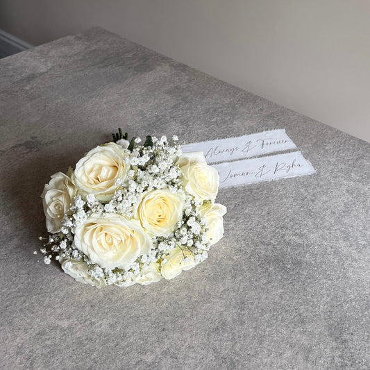 Bouquet of white roses on a gray surface with a name card.