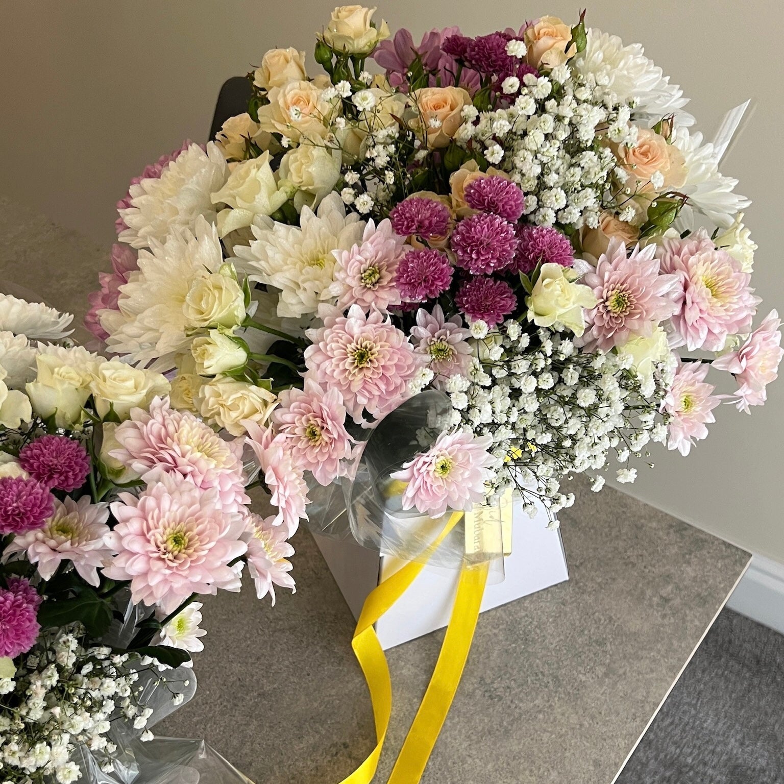 Bouquets of flowers in a box with a yellow ribbon on a gray surface