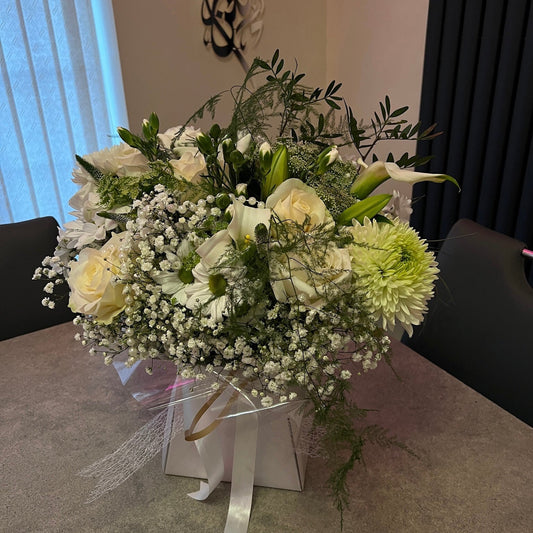 Bouquet of white and green flowers in a box on a table.
