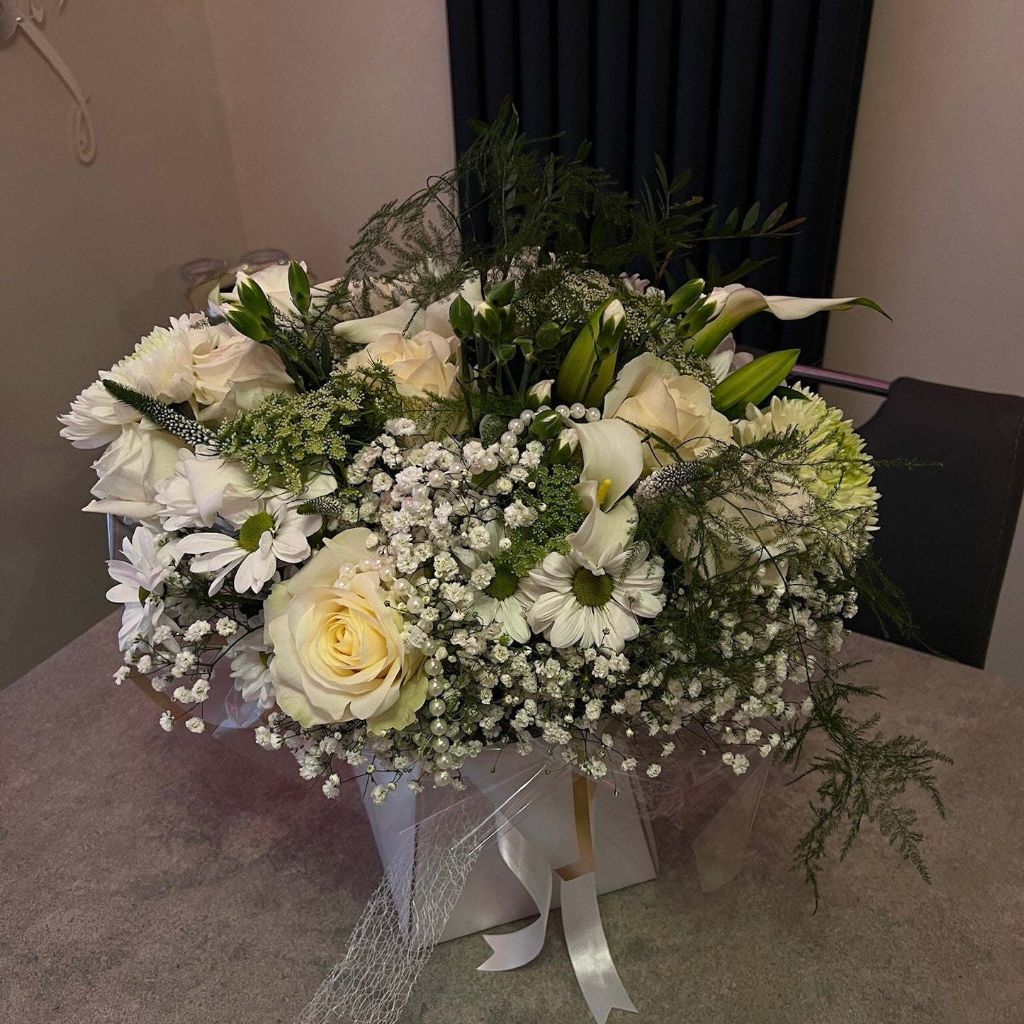Bouquet of white and green flowers in a box on a table.