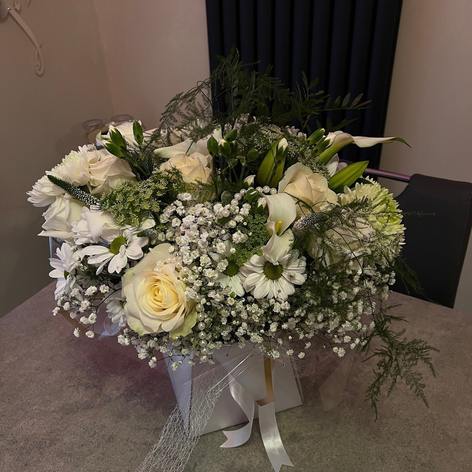 Bouquet of white and green flowers in a box on a table.