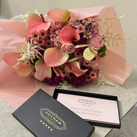 Bouquet of flowers with a Gotham gift card on a light surface