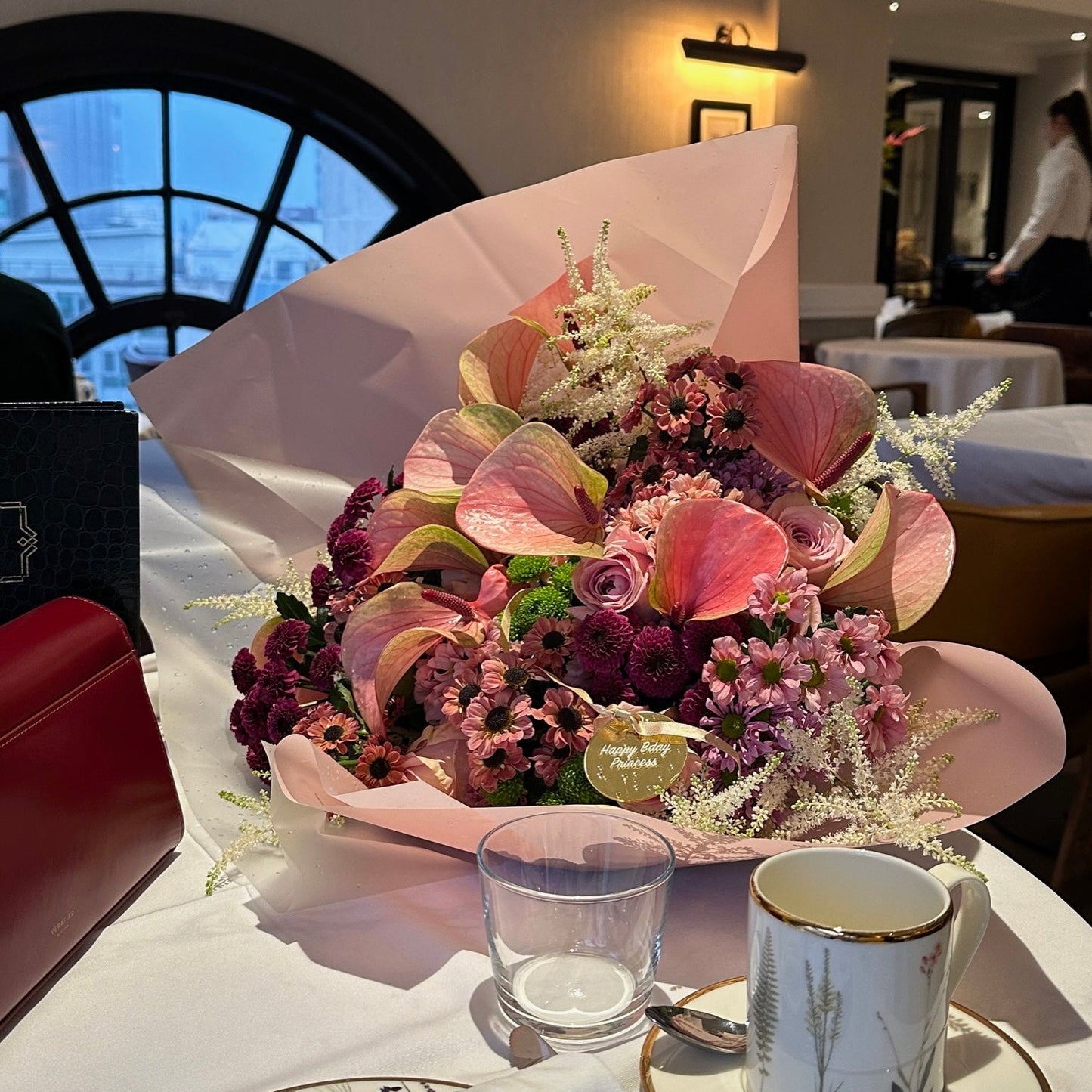 Floral arrangement on a table with a cup and saucer in a restaurant setting