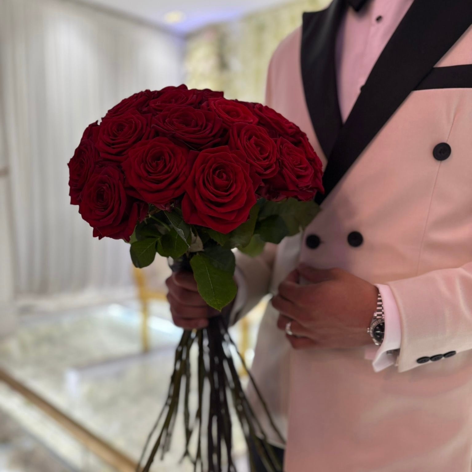Groom holding a bouquet of red roses in a wedding