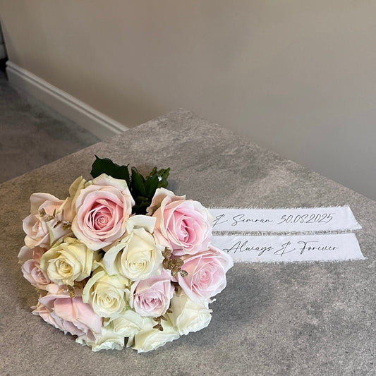 Bouquet of pink and white roses on a marble surface with a handwritten note.
