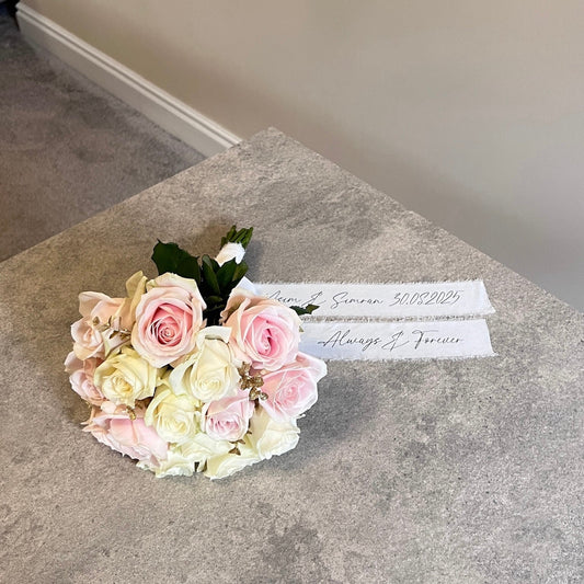 Bouquet of pink and white roses on a textured surface with a white riboon.