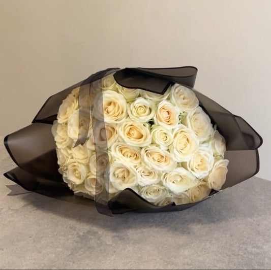 Bouquet of white roses wrapped in black paper on a neutral background